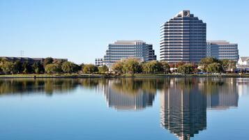 Un lago tranquilo que refleja edificios, incluyendo un rascacielos curvo destacado.