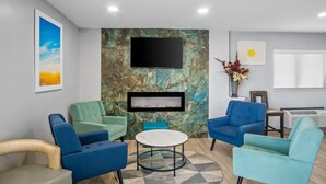 A modern lounge area with teal and blue upholstered chairs, a marble accent wall, a flat-screen TV, and a fireplace. - Days Inn by Wyndham Renfro Valley Mount Vernon (Mount Vernon)