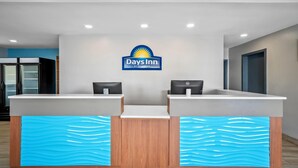 A reception desk with a Days Inn logo, two computer stations, and a blue wave-patterned counter. - Days Inn by Wyndham Renfro Valley Mount Vernon (Mount Vernon)