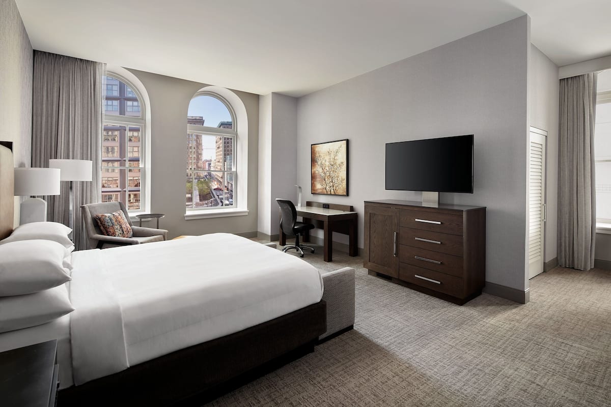 Une chambre d’hôtel avec un grand lit, un bureau, une télévision et une vue sur la ville par la fenêtre.