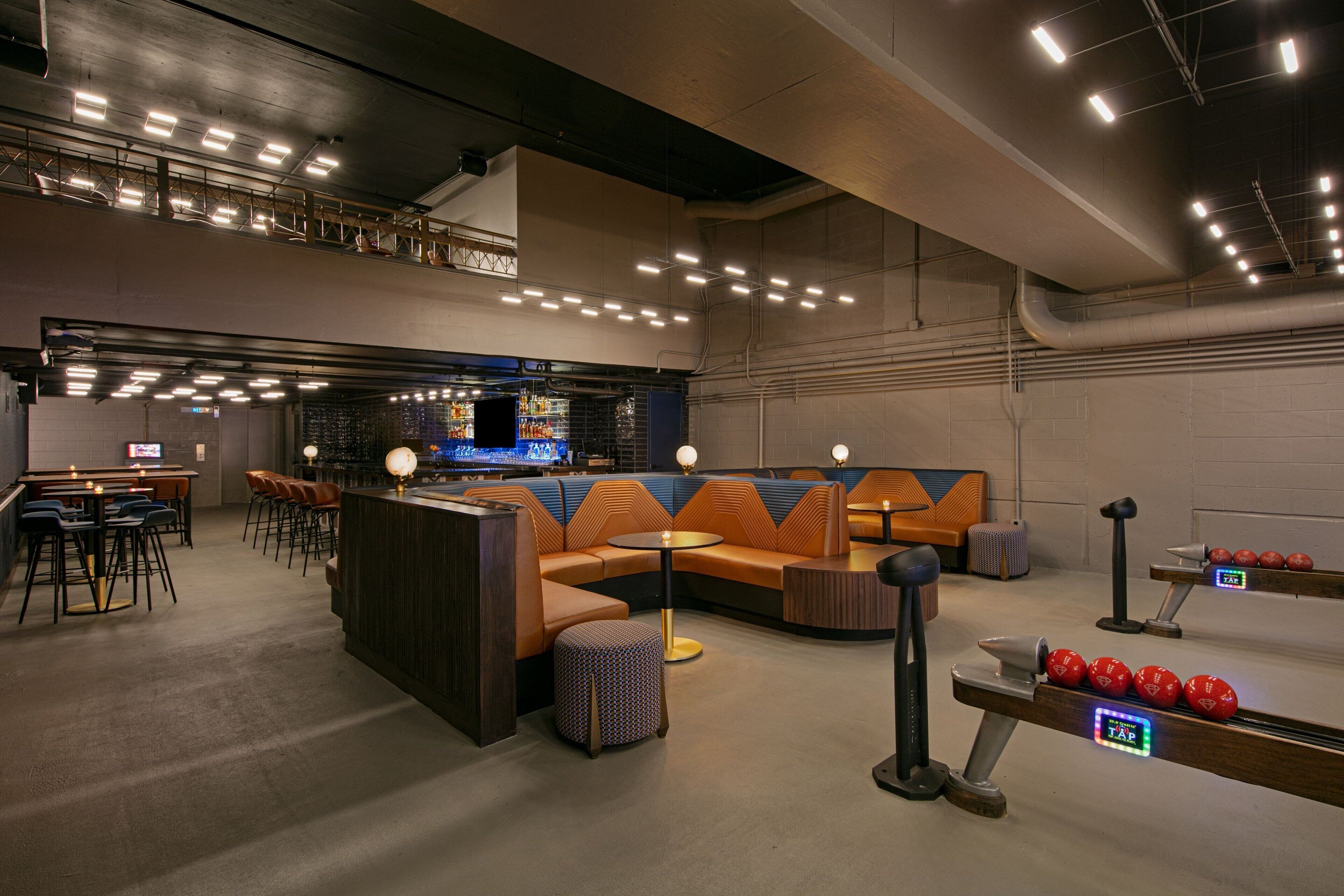 A modern lounge area with seating, a bar, and exercise equipment.