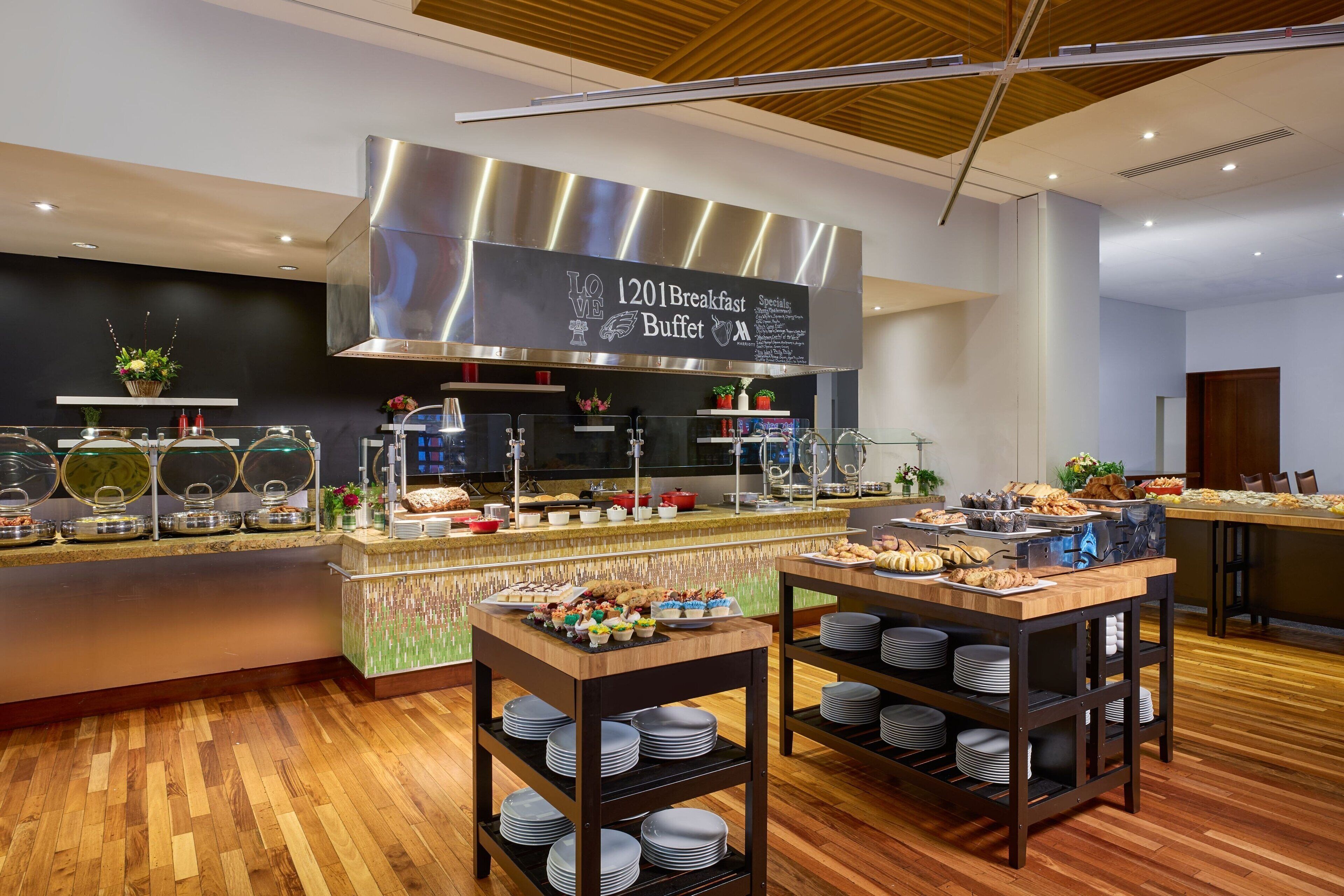 En morgenmadsbuffet med et rustfrit stål emfang, flere serveringsstationer og et bredt udvalg af mad.