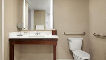 Un baño con tocador de madera, un lavabo blanco, un espejo, un inodoro y un perchero para toallas.
