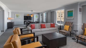 Una sala de estar moderna con un sofá gris, sillones de cuero, una mesa de centro y un televisor.