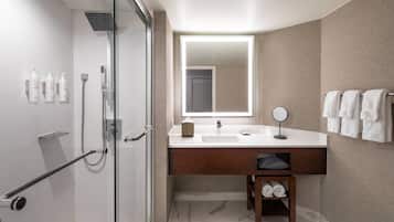 A modern bathroom with a glass shower enclosure, a white sink with a mirror, and a towel rack.