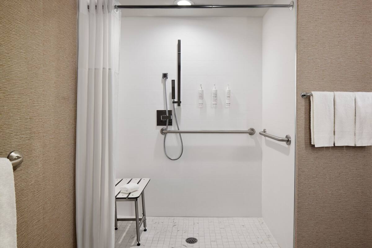 Une salle de bain moderne dotée d’une douche à l’italienne, d’un sèche-mains et d’un porte-serviettes.