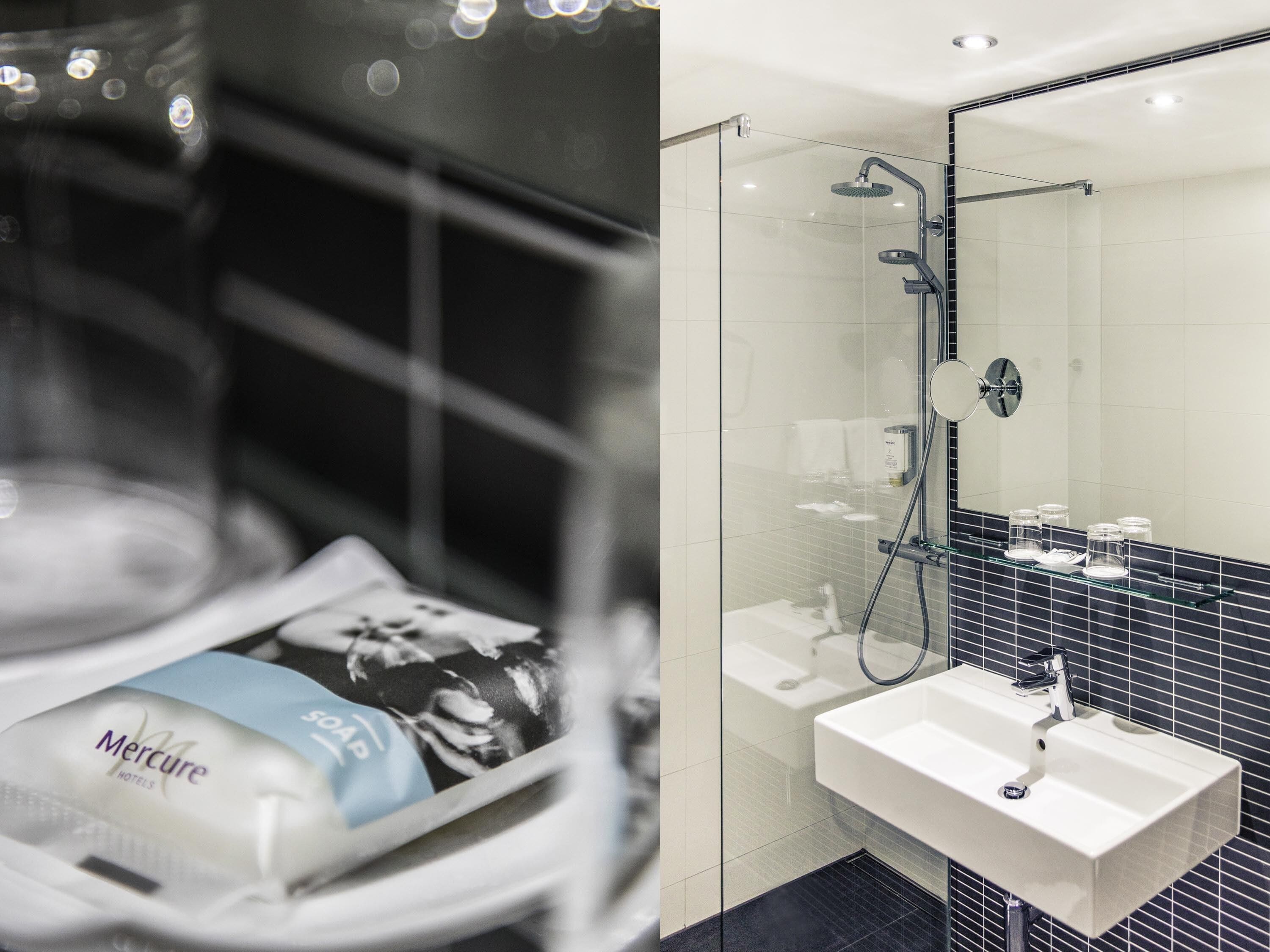 A modern bathroom with a glass shower enclosure, a white sink, and a mirror.
