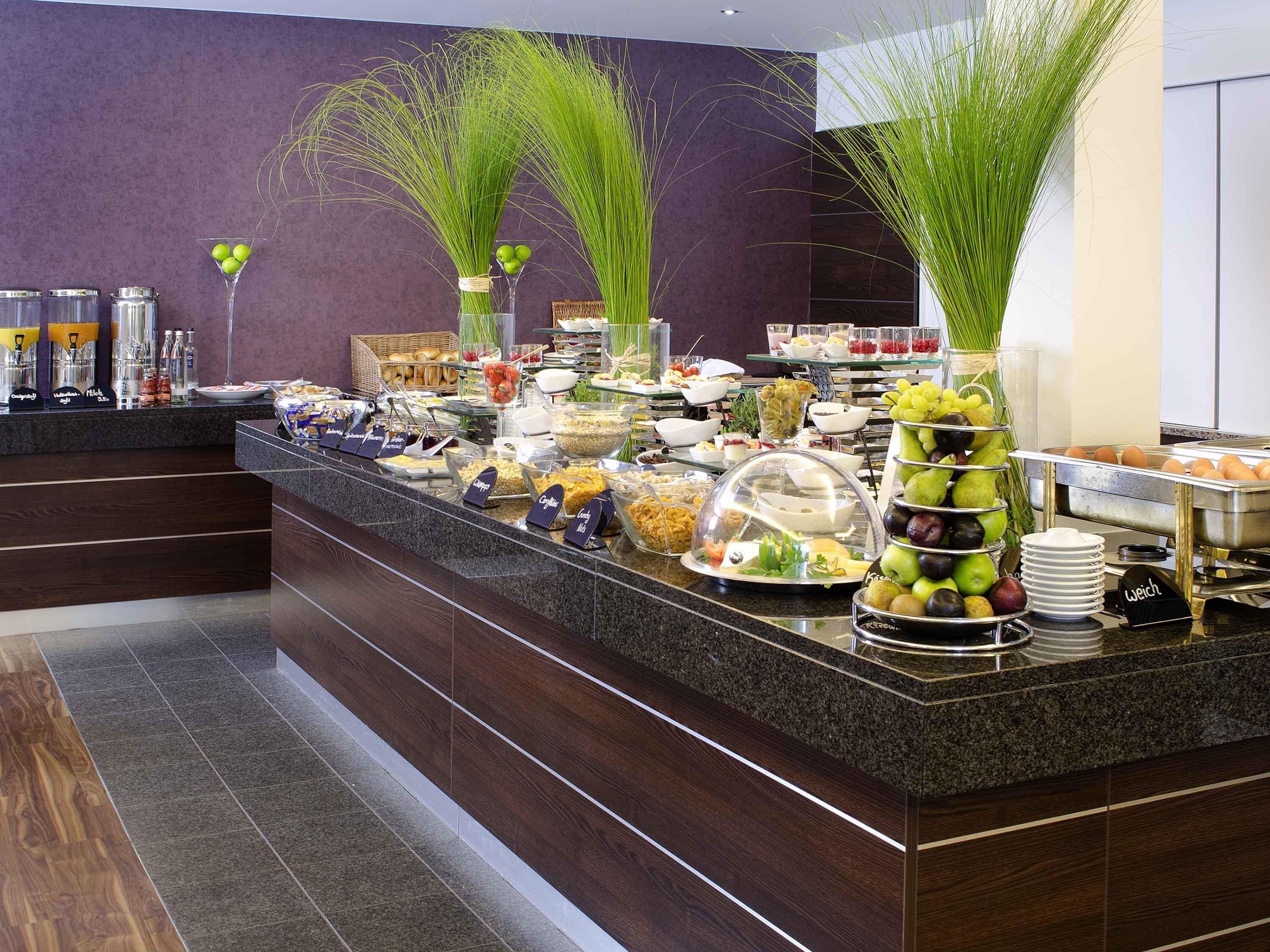 A buffet setup with various food items and a decorative plant arrangement.