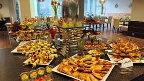 A buffet with various dishes and a decorative vase with flowers. - Mercure Hotel Luedenscheid (Luedenscheid)