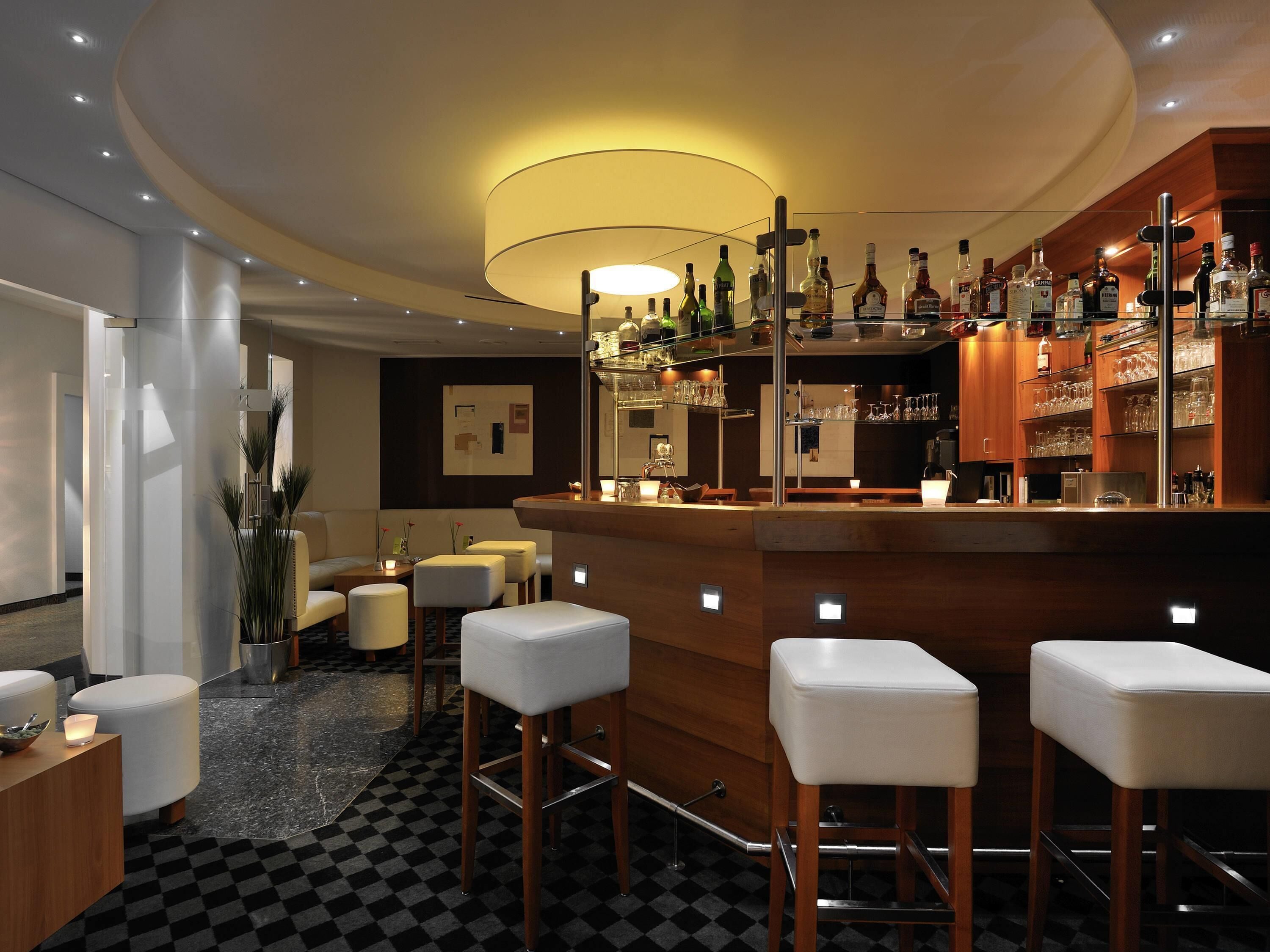A bar area with stools, a counter, and shelves with bottles.