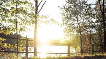 A wooden fence with a view of a body of water and trees in the background.