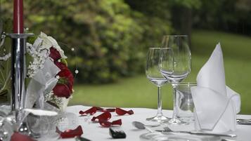 A table set with wine glasses, a red candle, and a bouquet of flowers.