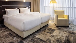 A hotel room with a large bed, a nightstand, a lamp, and a chair. - Mercure Hotel Luedenscheid (Luedenscheid)