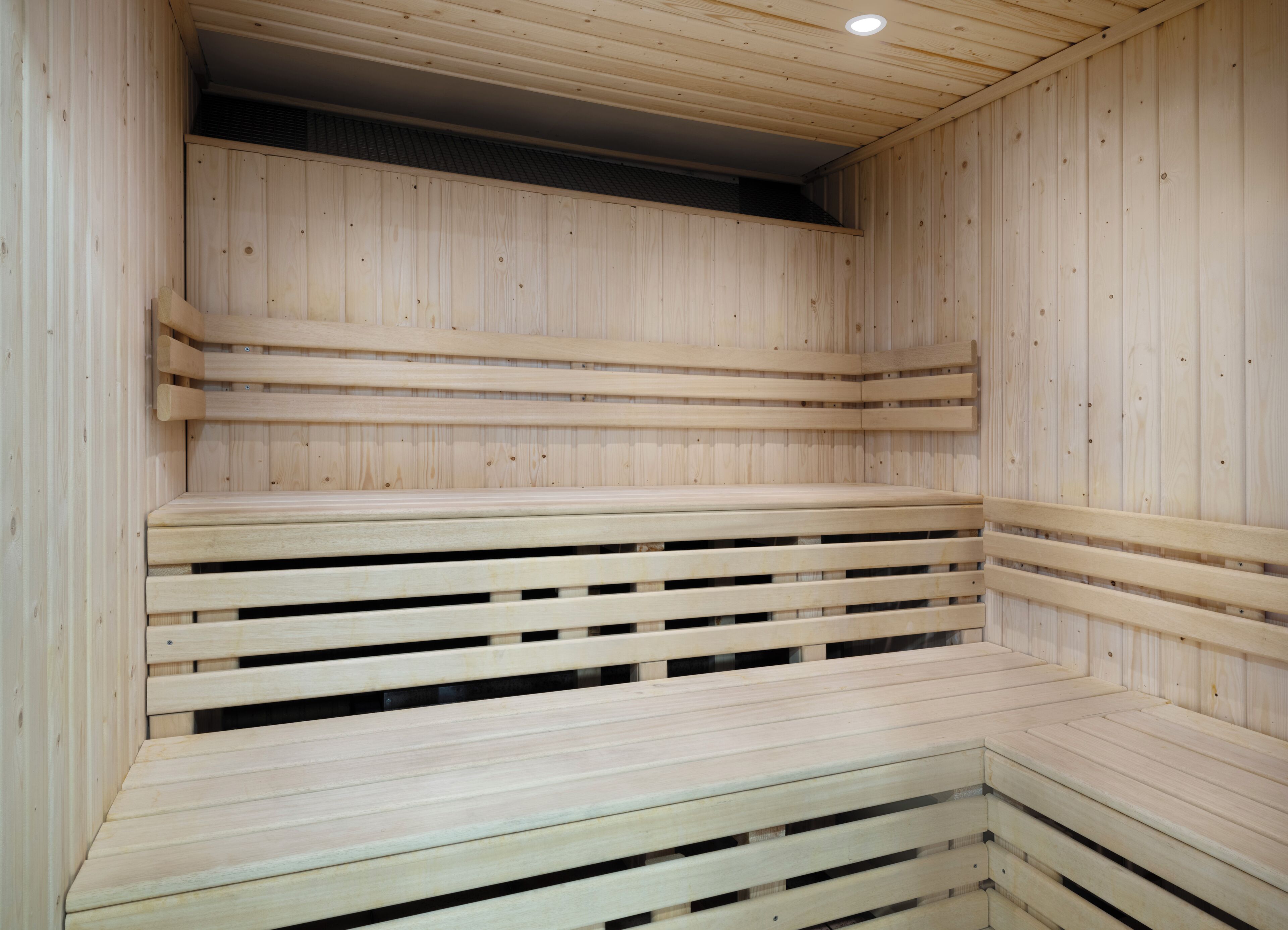 A sauna with wooden benches and a sloped ceiling.