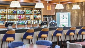 A bar area with a variety of liquor bottles, a cash register, and bar stools.