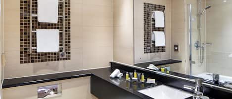 A modern bathroom with a black countertop, a white sink, and a glass-enclosed shower.