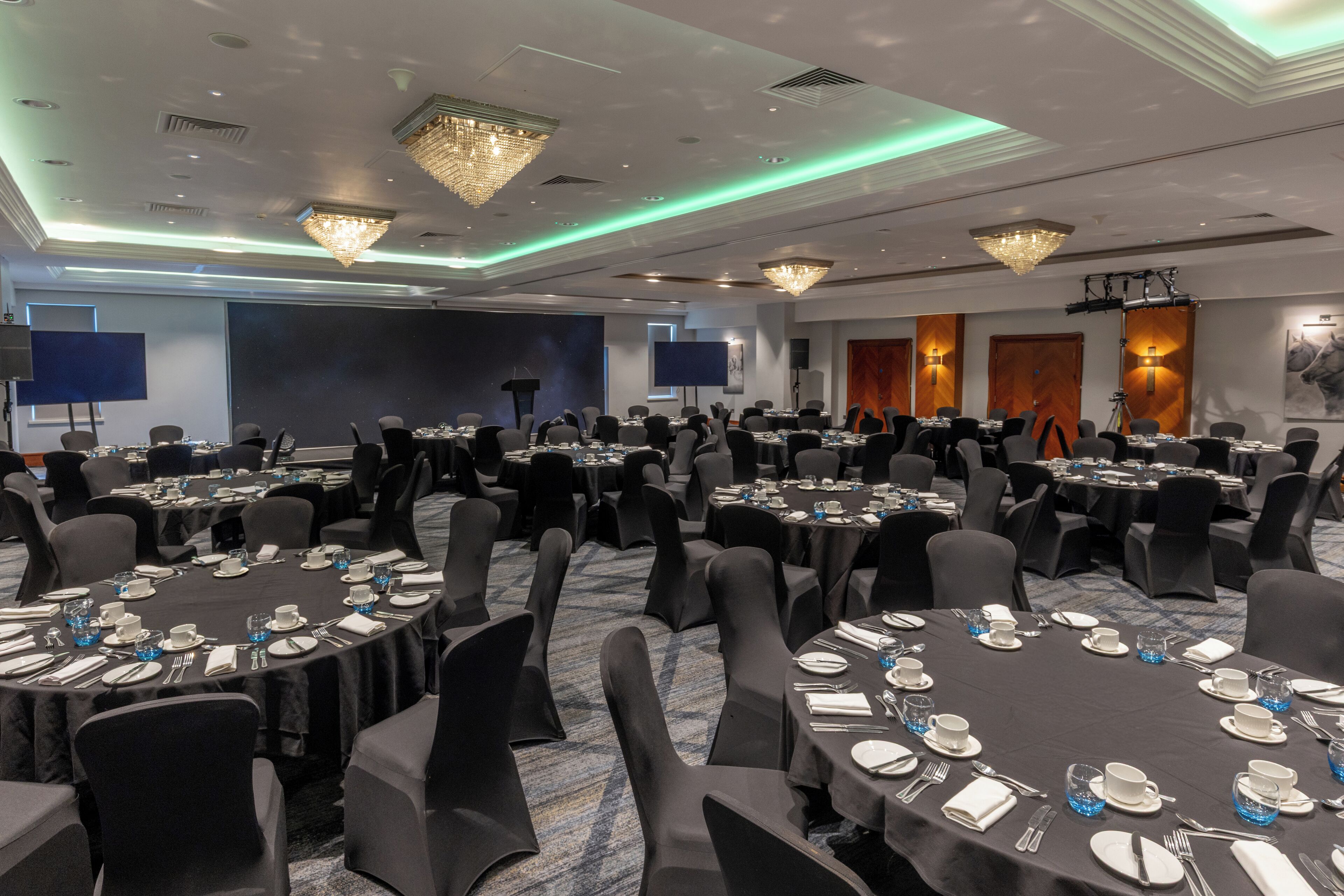 A conference room with round tables, black tablecloths, and chairs.