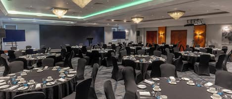 A conference room with round tables, black tablecloths, and chairs.