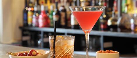 Un bar con una copa de martini, una copa de cóctel y un cuenco de nueces.