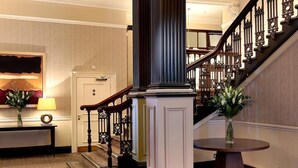A grand staircase with ornate railings, a polished wooden floor, and a column with a dark base. - Macdonald New Blossoms Hotel, Chester (Chester)