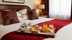 A neatly made bed with a tray of breakfast items including eggs, toast, and juice, in a hotel room with a framed picture on the wall. - Macdonald New Blossoms Hotel, Chester (Chester)
