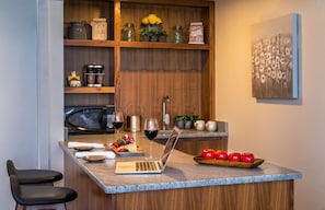 A modern kitchen with a built-in microwave, a laptop on the counter, and a fruit bowl.
