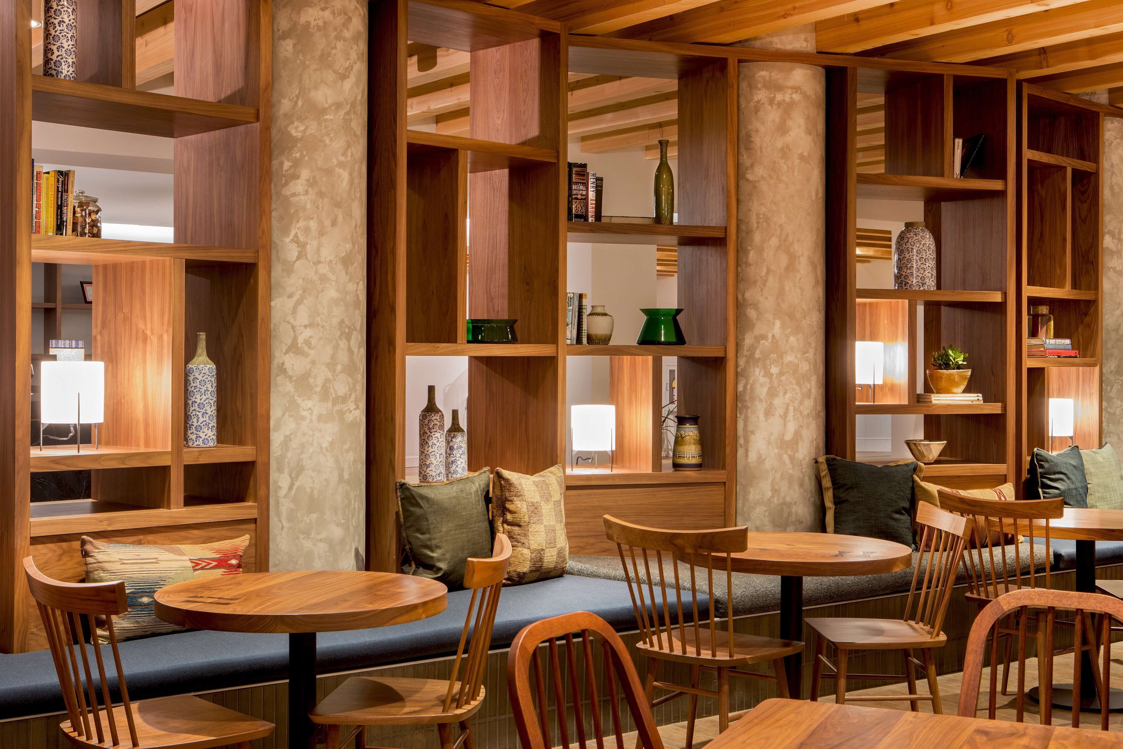A cozy cafe with wooden furniture, shelves with books and decorative items, and a comfortable seating area.