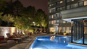 A swimming pool area with lounge chairs and a stone wall. - DoubleTree by Hilton Atlanta Windy Hill Ballpark (Atlanta)