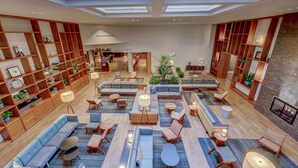 A spacious lobby with multiple seating areas, a large bookshelf, and a fireplace. - DoubleTree by Hilton Atlanta Windy Hill Ballpark (Atlanta)