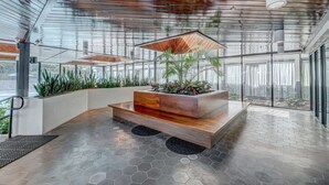 A modern interior with a wooden bench, a planter with plants, and a glass wall. - DoubleTree by Hilton Atlanta Windy Hill Ballpark (Atlanta)