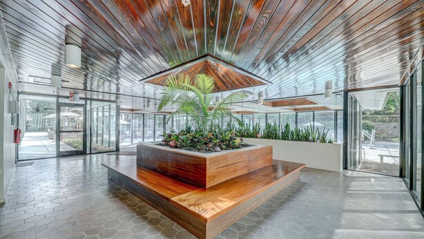 A modern lobby with a central wooden planter, glass doors, and a hexagonal tiled floor. - DoubleTree by Hilton Atlanta Windy Hill Ballpark (Atlanta)