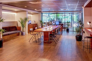 A modern conference room with a long table, chairs, and potted plants.