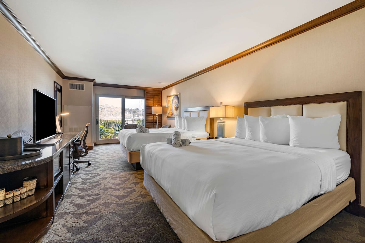 Une chambre d’hôtel avec un grand lit, un bureau doté d’une télévision à écran plat, une chaise et une vue sur la ville.