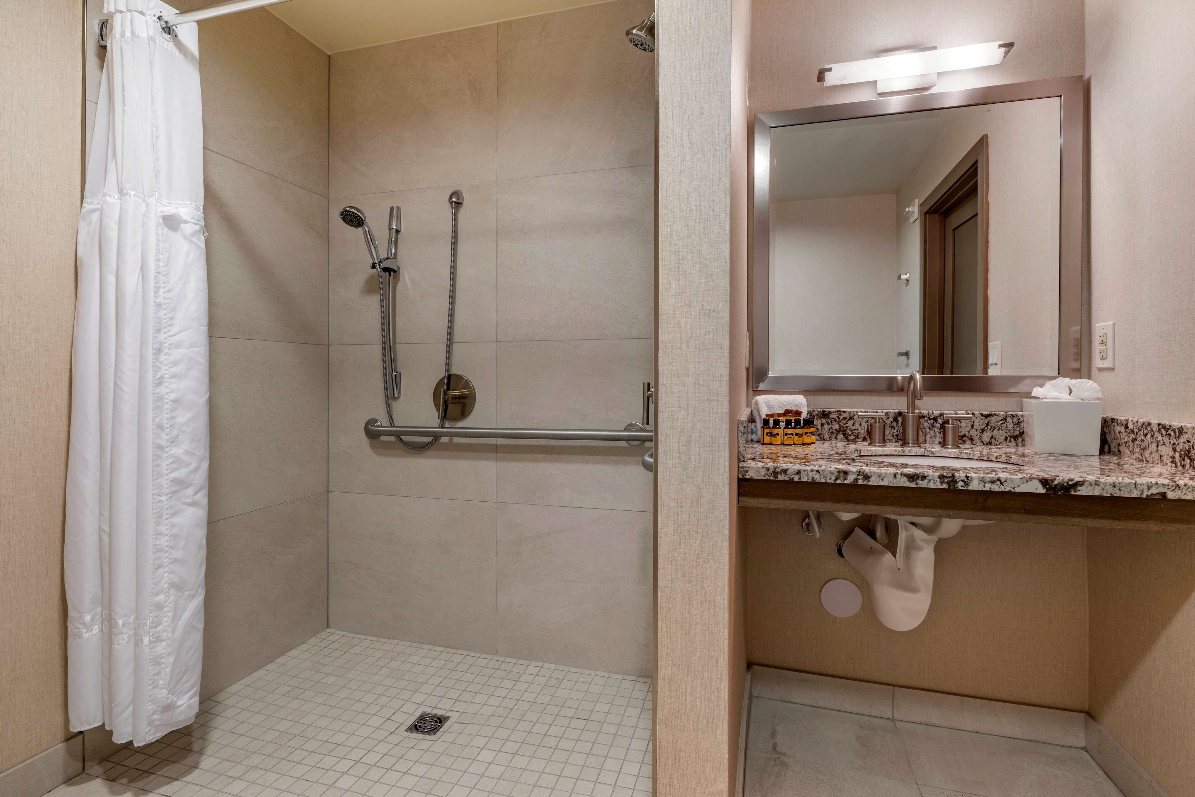 Une salle de bain avec une douche, un lavabo avec un miroir et un porte-serviettes.