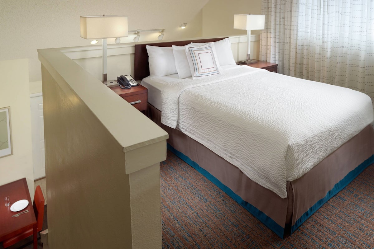 A hotel room with a bed, bedside tables, lamps, and a telephone.