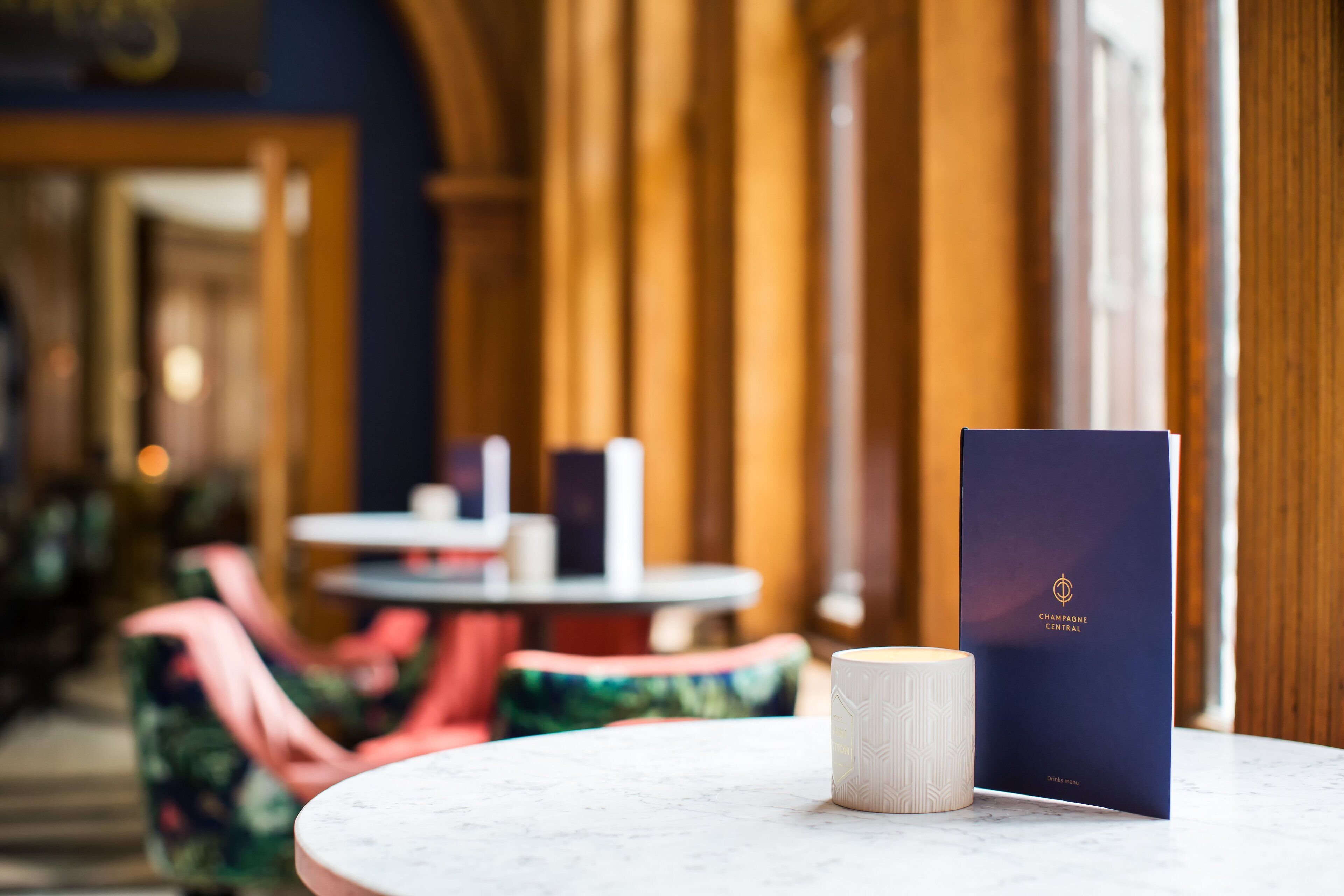 A marble table with a blue booklet and a white candle.