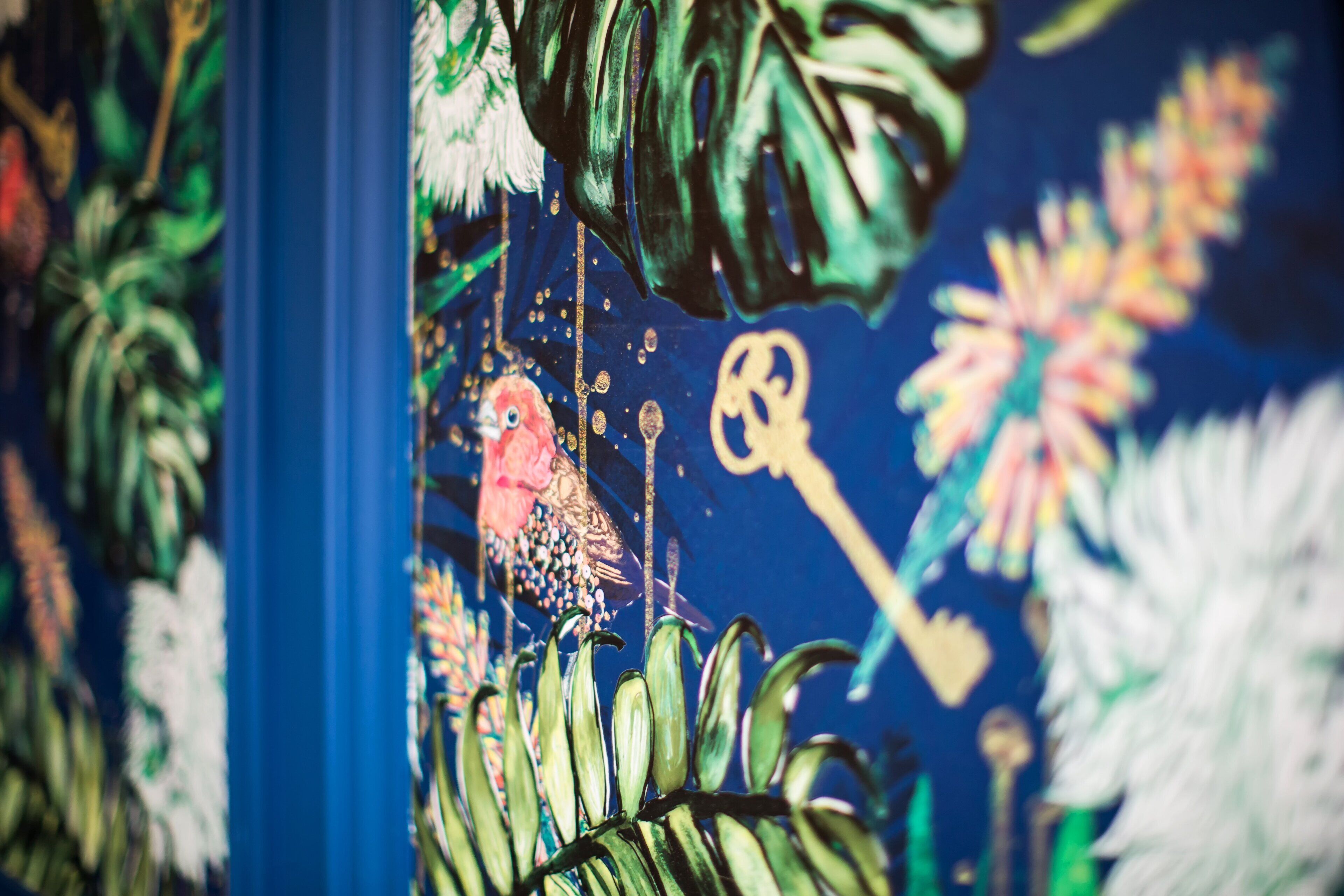 Une fresque colorée représentant un oiseau, une clé et des motifs floraux.