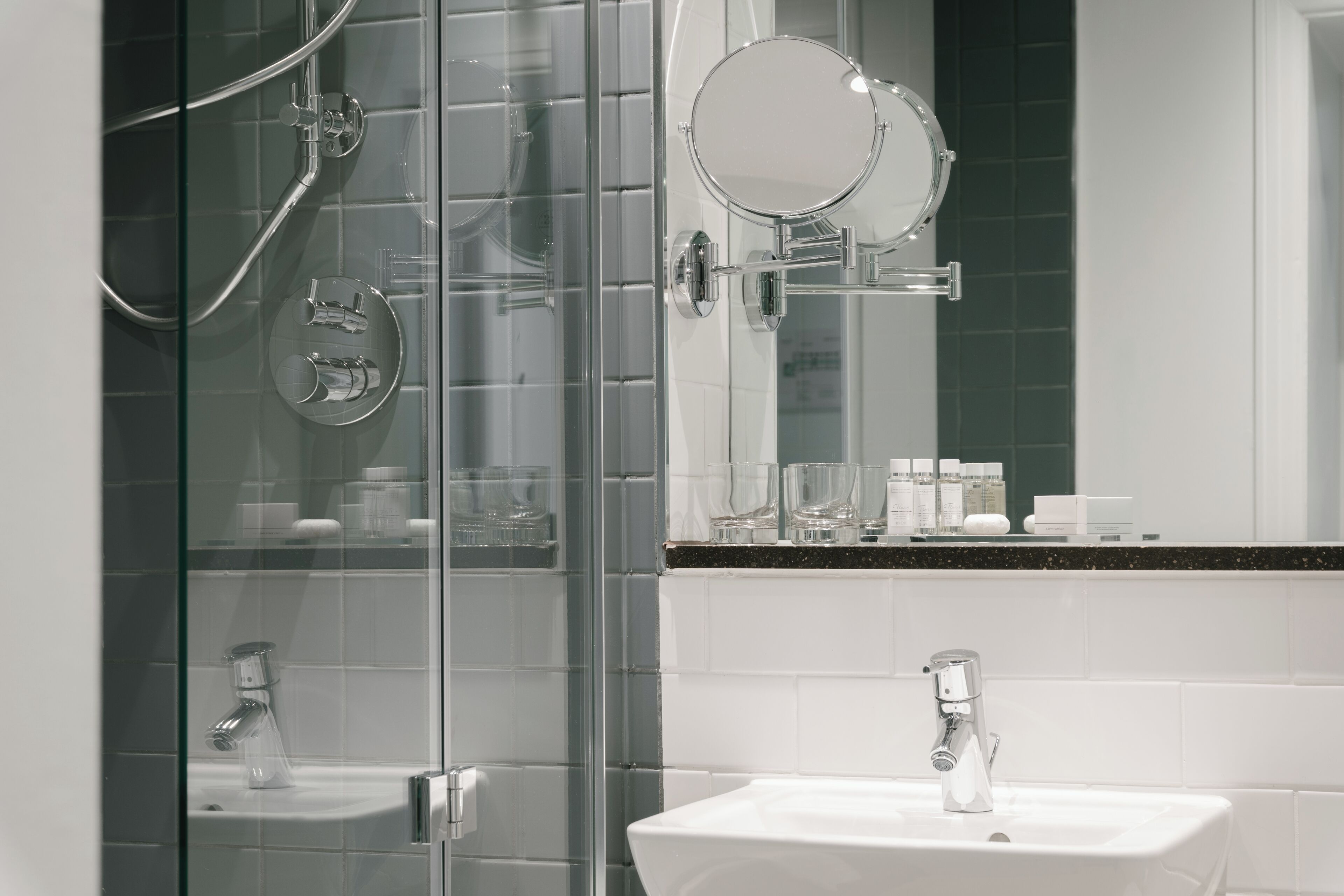 Une salle de bain moderne avec une douche à parois de verre, un lavabo blanc et un miroir au-dessus du lavabo.