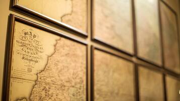A wall with multiple framed maps and documents.