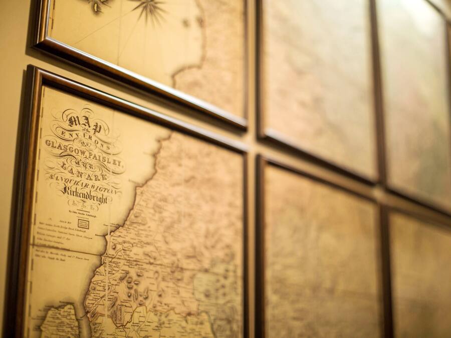 A wall with multiple framed maps and documents.