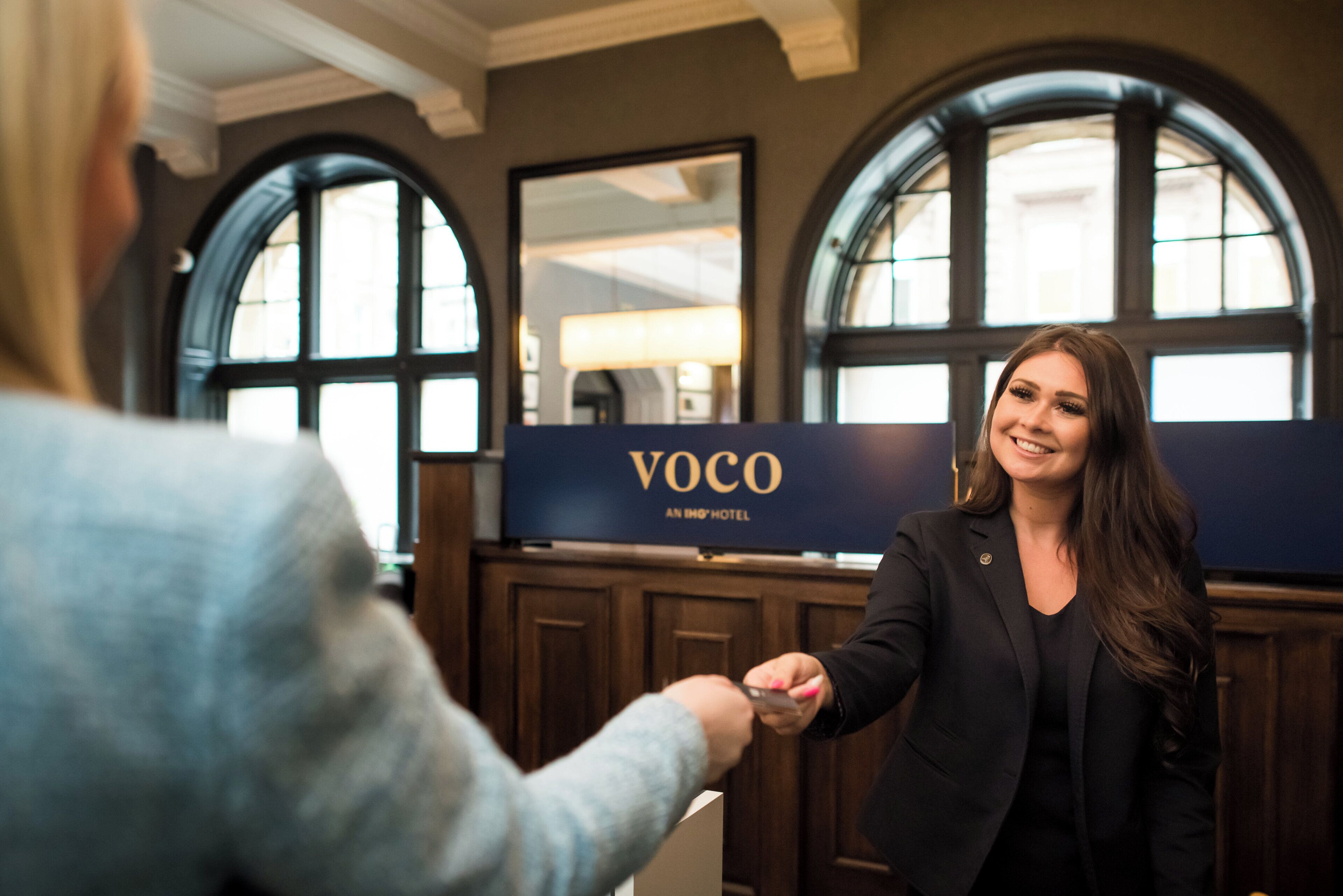 Un área de recepción con un cartel que dice "VOCO An Inn Hotel".