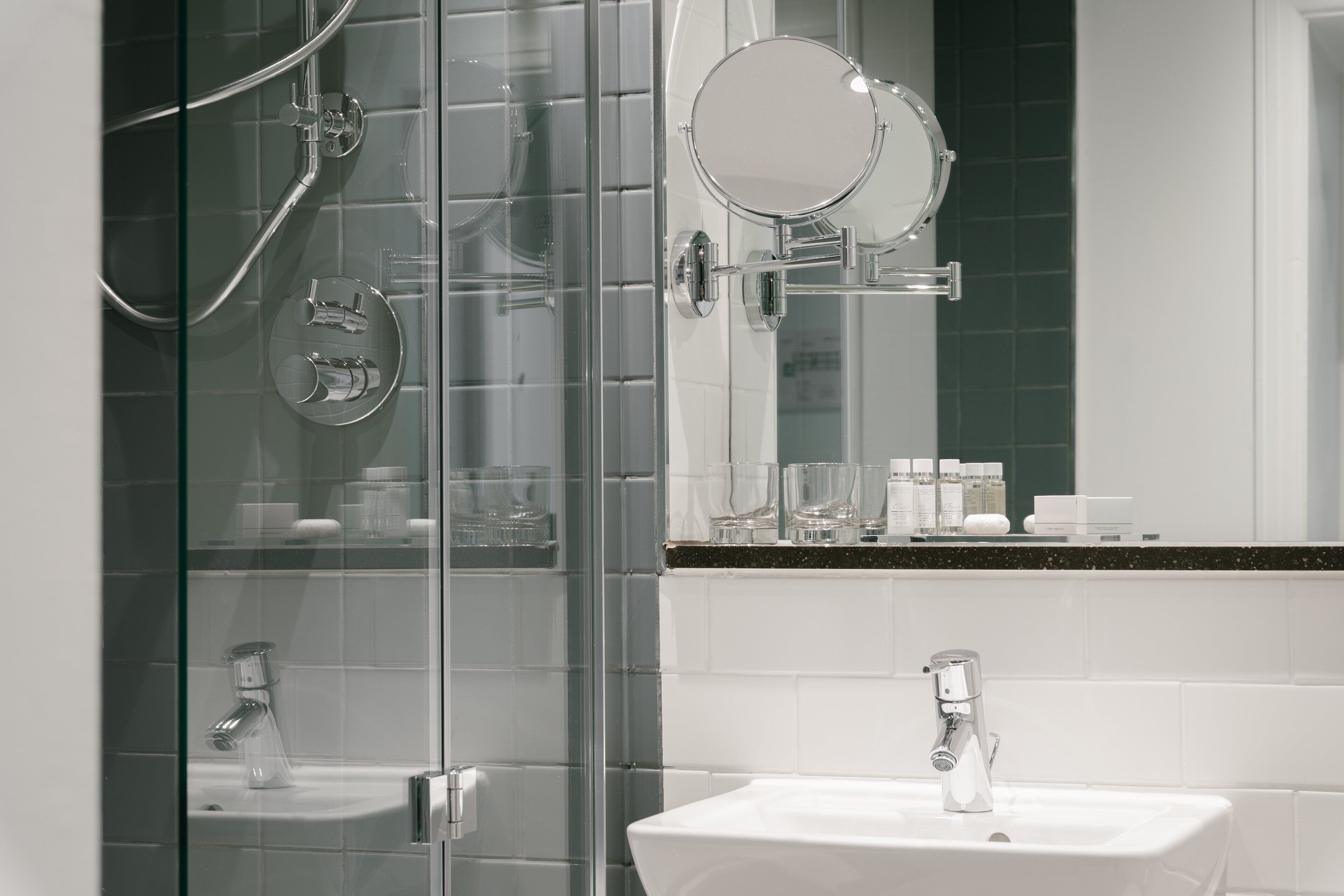 A modern bathroom with a glass shower enclosure, a white sink, and a mirror above the sink.