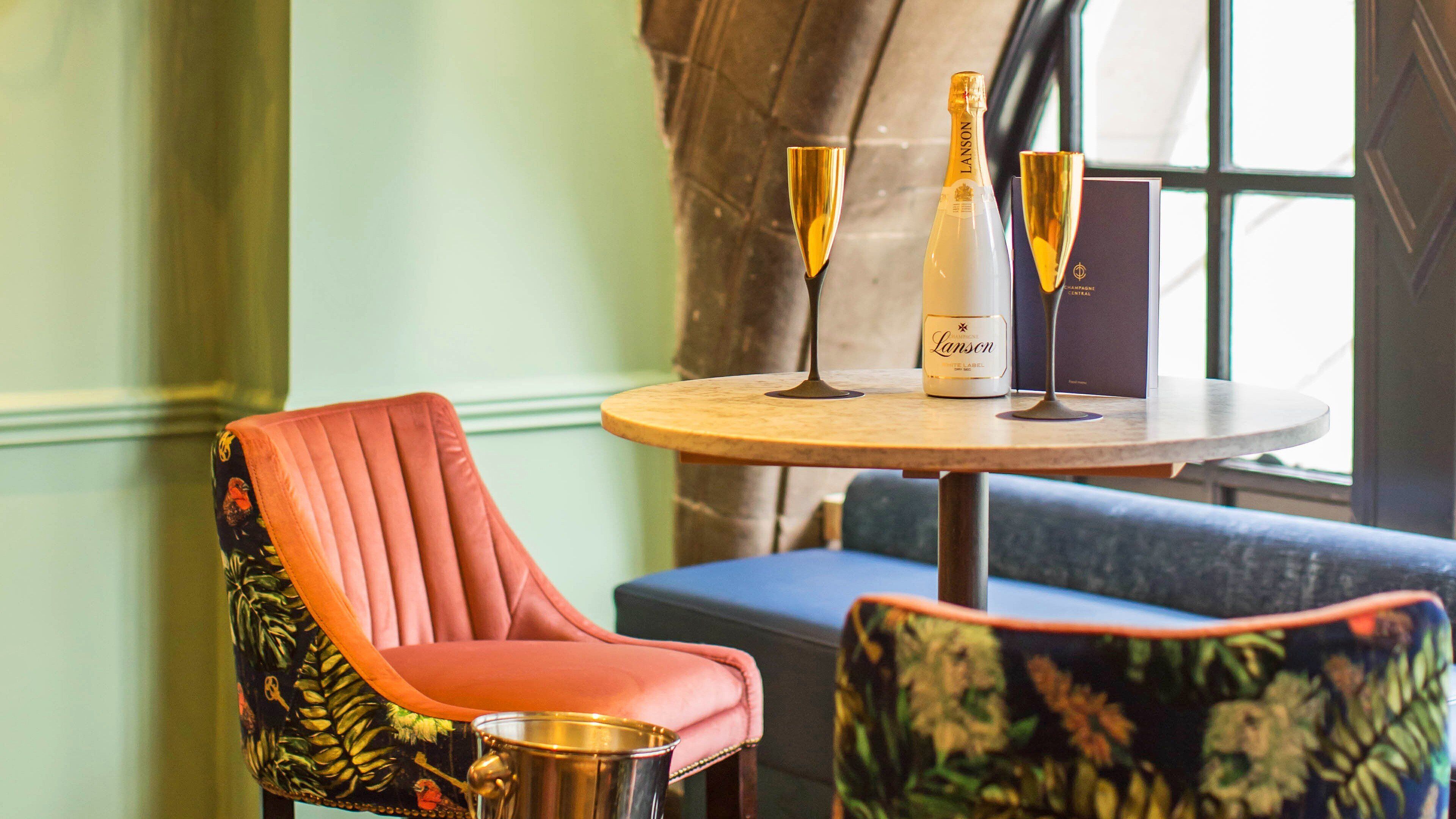 A table with a bottle of champagne, two glasses, and a menu.