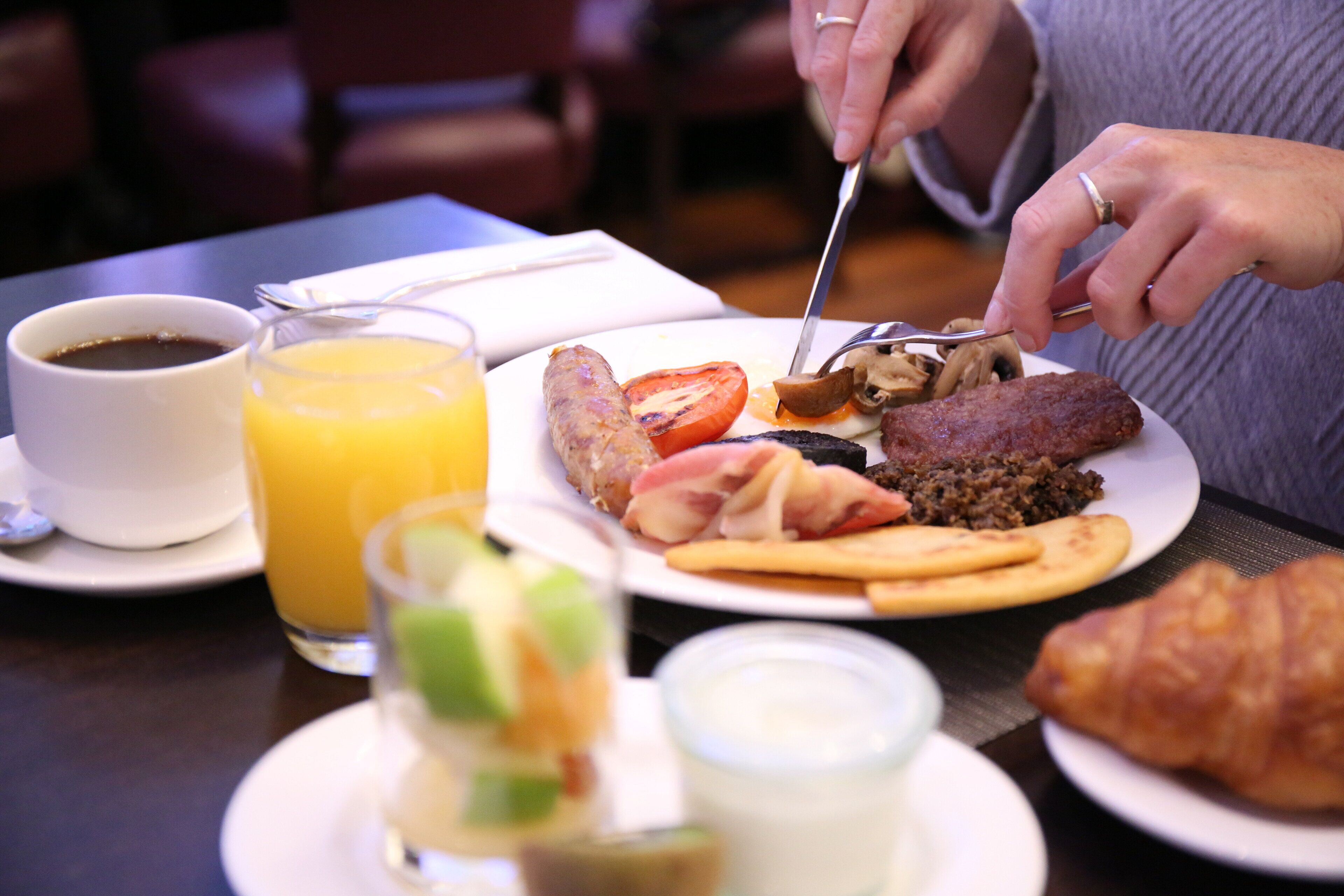 A breakfast setting with a plate of food, a glass of orange juice, and a cup of coffee.