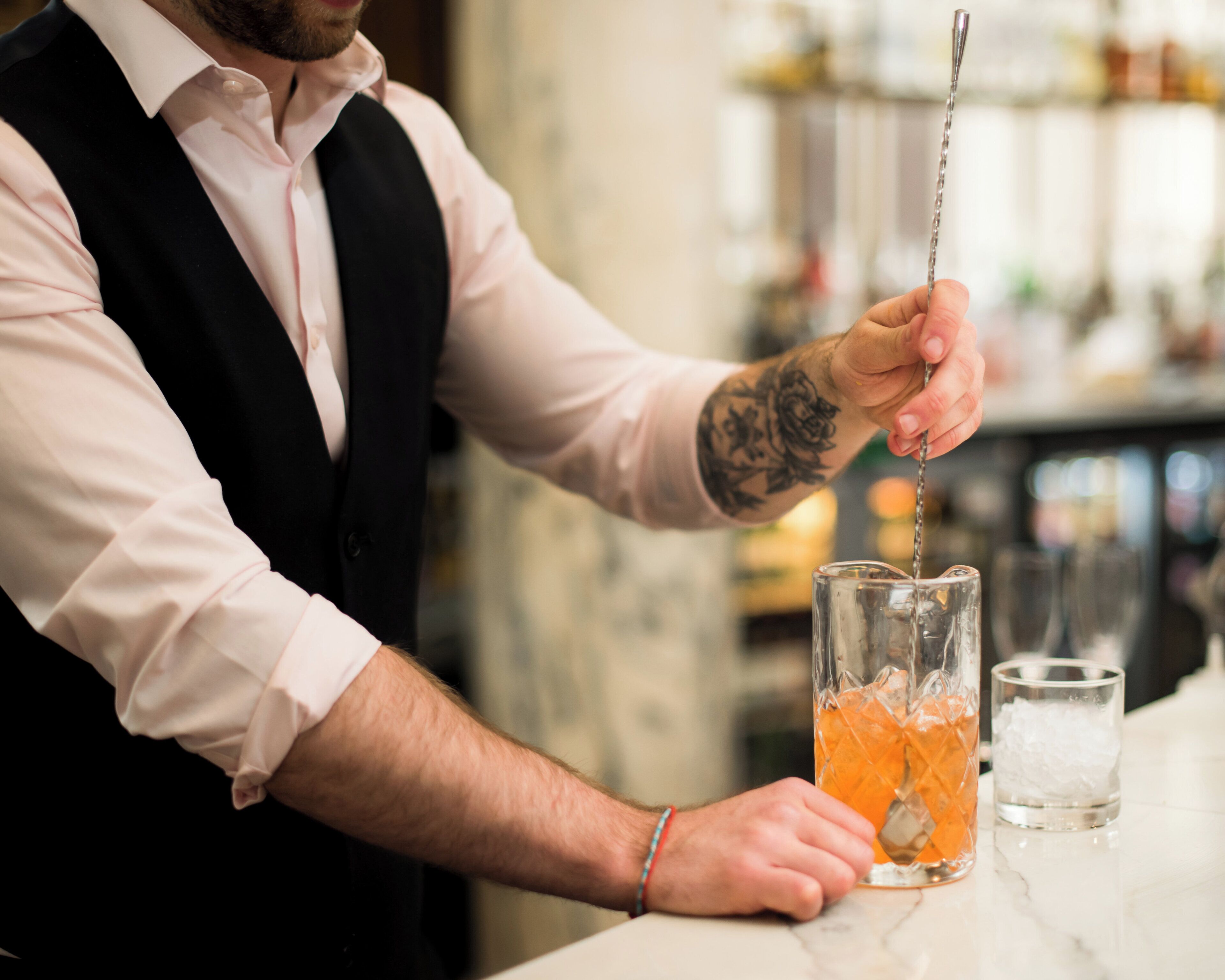 Un barman prépare un cocktail à l’aide d’un shaker et d’un verre.