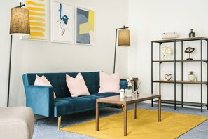A modern living room with a teal sofa, a wooden coffee table, and a yellow rug. - voco Grand Central Glasgow by IHG (Glasgow)