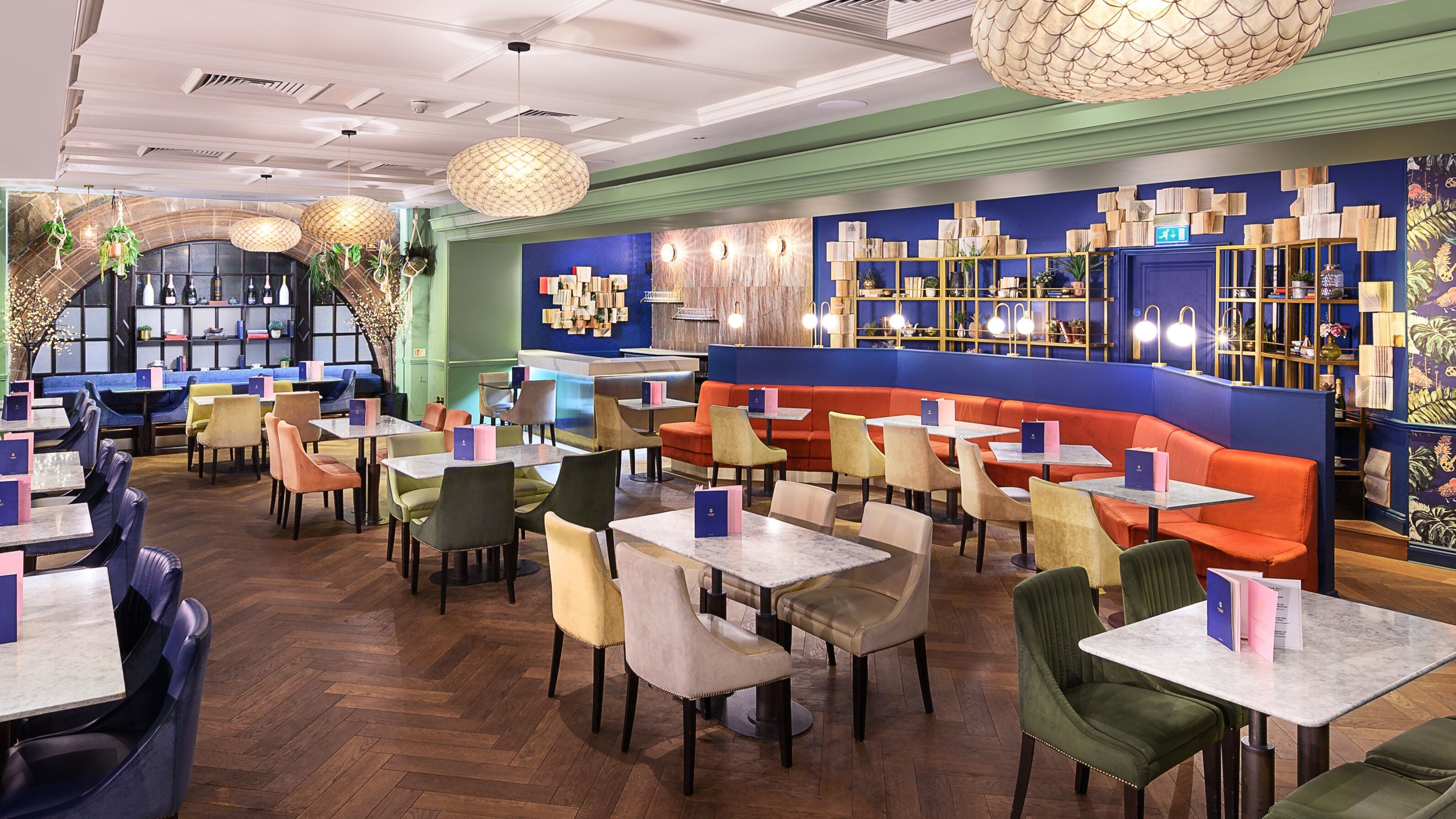 A restaurant with multiple seating areas, including booths and tables, and a bar area with shelves of bottles and glasses.