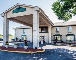 A hotel entrance with a covered waiting area, numbered 4995, and potted plants in the foreground. - Quality Inn & Suites Des Moines - Merle Hay Road (Des Moines)