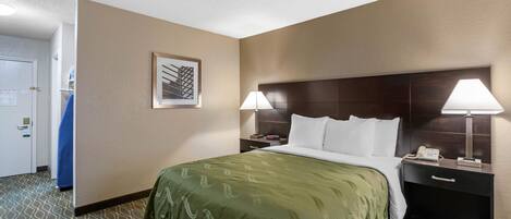 Habitación de hotel con una cama grande, dos lámparas de noche, una mesita con un teléfono y un cuadro enmarcado en la pared.