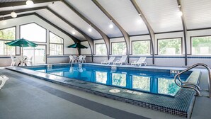 Ein Hallenbad mit deutlichen Markierungen, Liegestühlen und Sonnenschirmen.